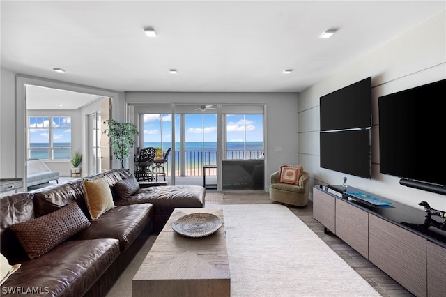 living room with light wood-type flooring, a water view, and a healthy amount of sunlight