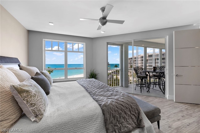 bedroom featuring a water view, access to outside, and light hardwood / wood-style flooring