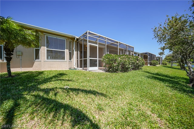 back of house with glass enclosure and a lawn