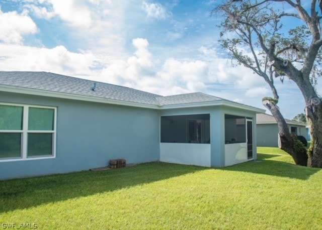 back of property with a lawn and a sunroom