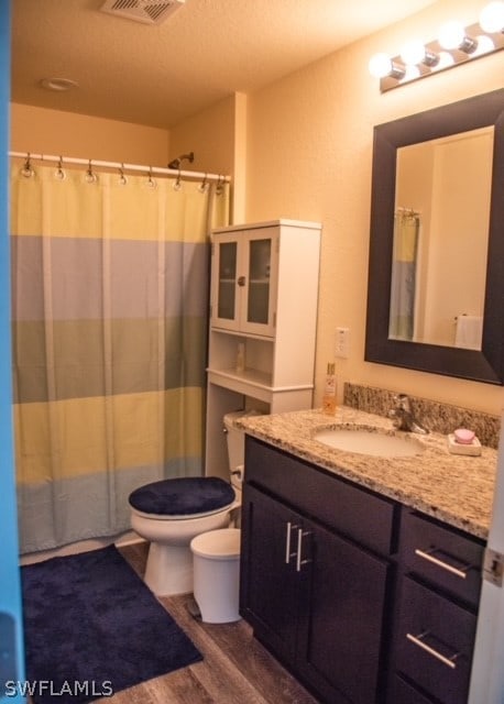 bathroom featuring vanity with extensive cabinet space, toilet, and hardwood / wood-style flooring