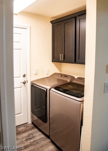 laundry area featuring dark hardwood / wood-style flooring, washing machine and clothes dryer, and cabinets