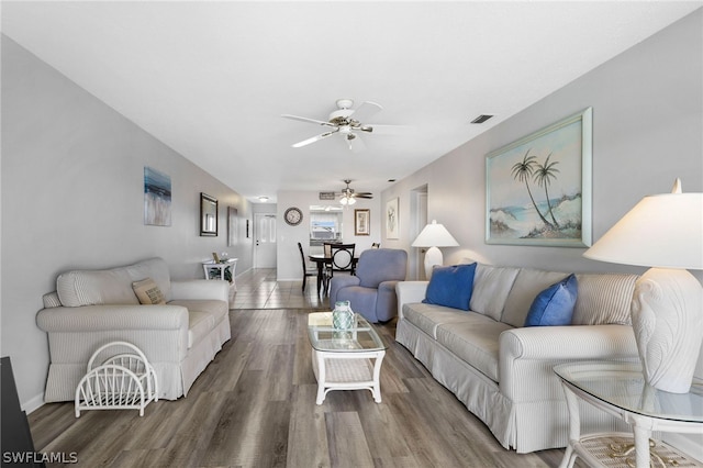 living area with visible vents, baseboards, ceiling fan, and wood finished floors