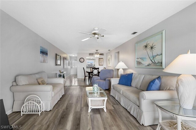 living area with visible vents, baseboards, ceiling fan, and wood finished floors