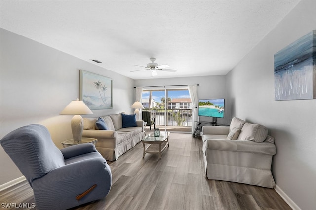 living room featuring hardwood / wood-style flooring, ceiling fan, and a textured ceiling