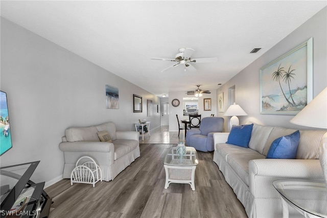 living area featuring visible vents, baseboards, and wood finished floors