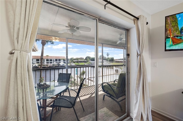 sunroom / solarium featuring a healthy amount of sunlight, a ceiling fan, and a water view