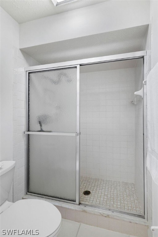 bathroom featuring tile patterned floors, an enclosed shower, and toilet