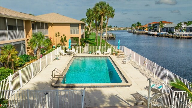 community pool featuring a patio, fence, and a water view