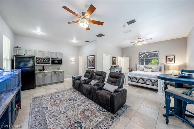 tiled bedroom featuring multiple windows, ceiling fan, and black fridge