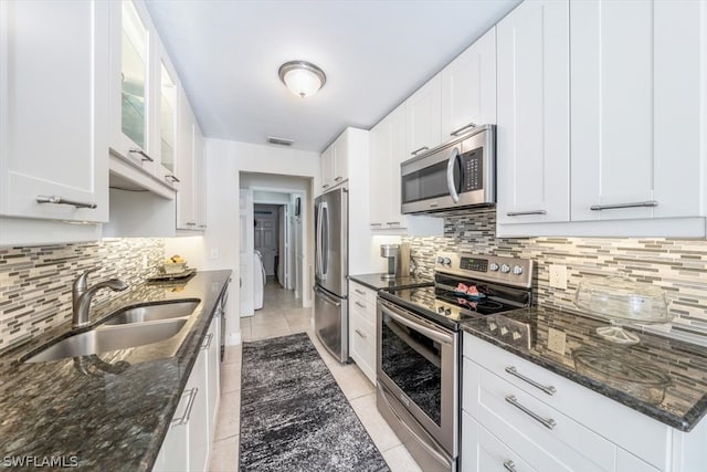 kitchen featuring white cabinets, stainless steel appliances, sink, and dark stone counters