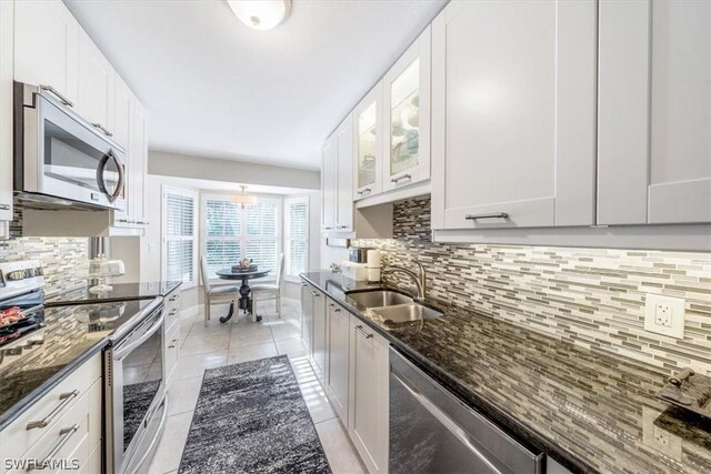 kitchen with appliances with stainless steel finishes, dark stone counters, sink, and white cabinets