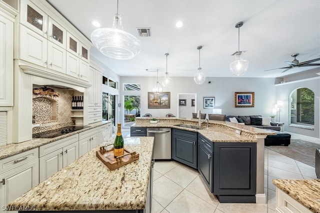 kitchen featuring black electric cooktop, stainless steel dishwasher, a kitchen island with sink, and pendant lighting