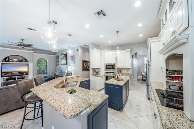 kitchen featuring a kitchen island with sink, sink, hanging light fixtures, stainless steel appliances, and blue cabinets