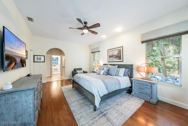 bedroom featuring ceiling fan, dark hardwood / wood-style flooring, and multiple windows