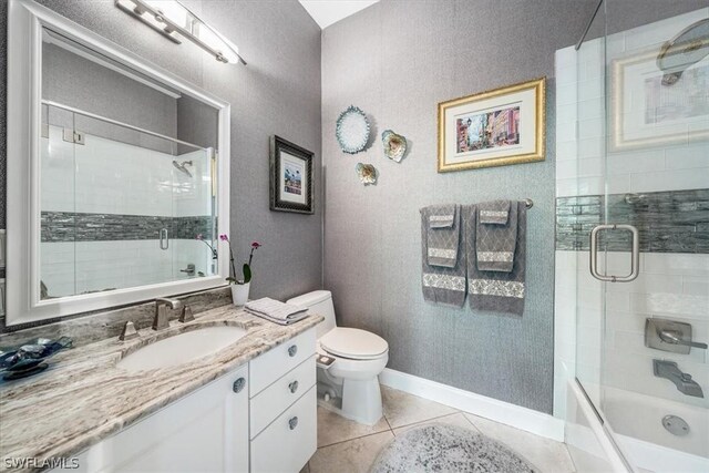 full bathroom with shower / bath combination with glass door, tile patterned flooring, vanity, and toilet