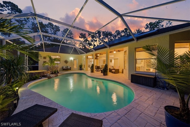 pool at dusk featuring glass enclosure and a patio area