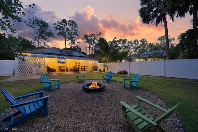 playground at dusk with a lawn, a patio area, and an outdoor fire pit