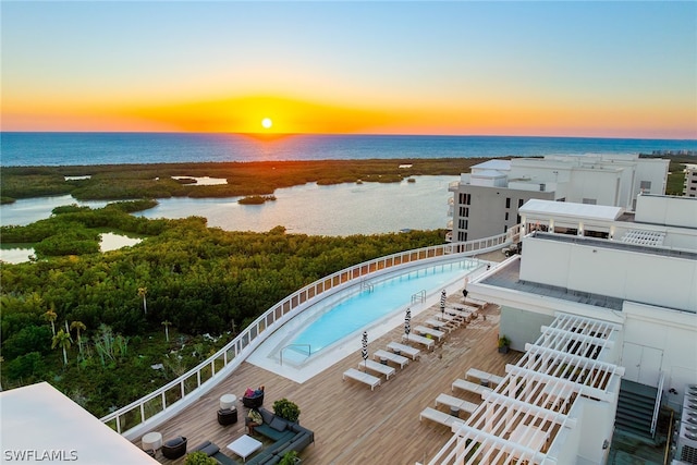 pool at dusk featuring central AC unit and a water view