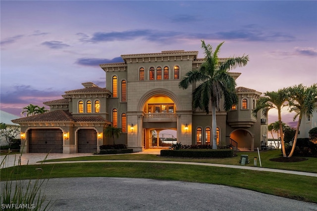 mediterranean / spanish-style home with a yard, a garage, and a balcony