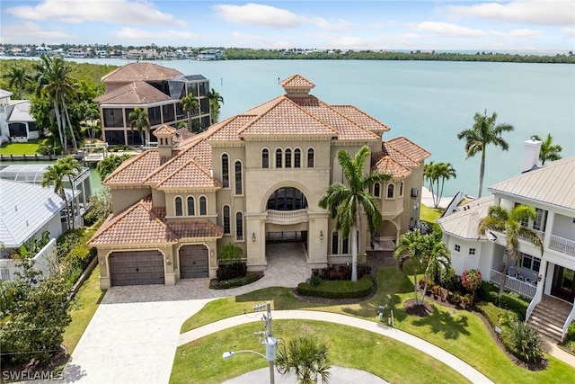 view of front of property featuring a garage, a water view, a front lawn, and a balcony