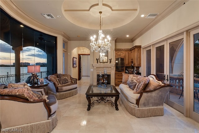 living room with a water view, a raised ceiling, a notable chandelier, and light tile floors