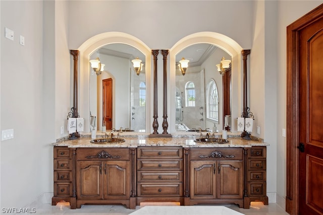 bathroom featuring ornate columns, crown molding, double vanity, and tile flooring