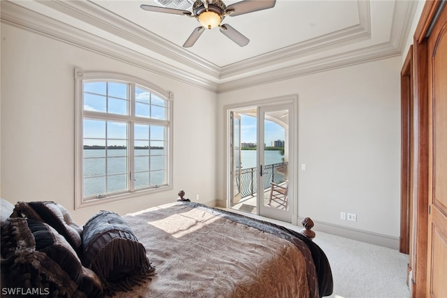 carpeted bedroom with access to outside, crown molding, a tray ceiling, a water view, and ceiling fan