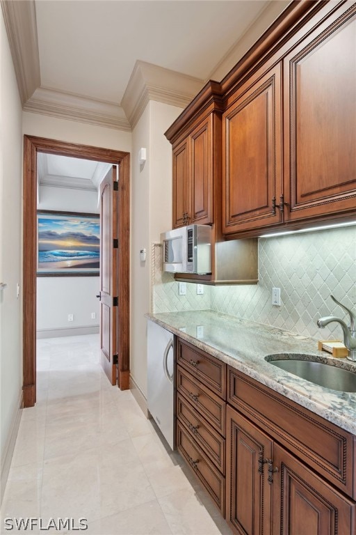 kitchen with tasteful backsplash, light stone countertops, sink, and light tile floors