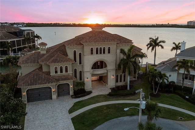 mediterranean / spanish-style house featuring a yard, a garage, and a water view