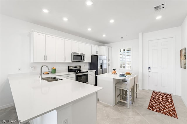 kitchen featuring a breakfast bar area, a sink, visible vents, light countertops, and appliances with stainless steel finishes