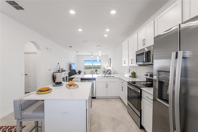 kitchen featuring stainless steel appliances, light countertops, a sink, and a breakfast bar area