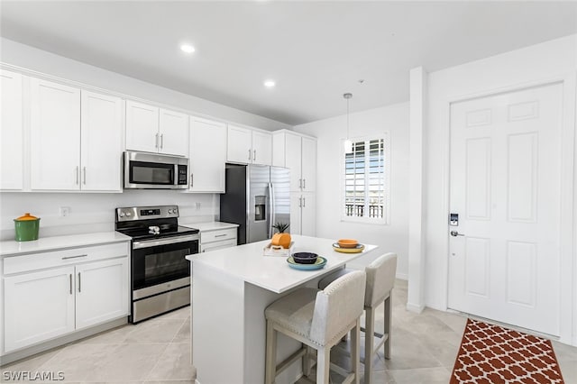 kitchen with white cabinets, a breakfast bar, a center island, stainless steel appliances, and light countertops