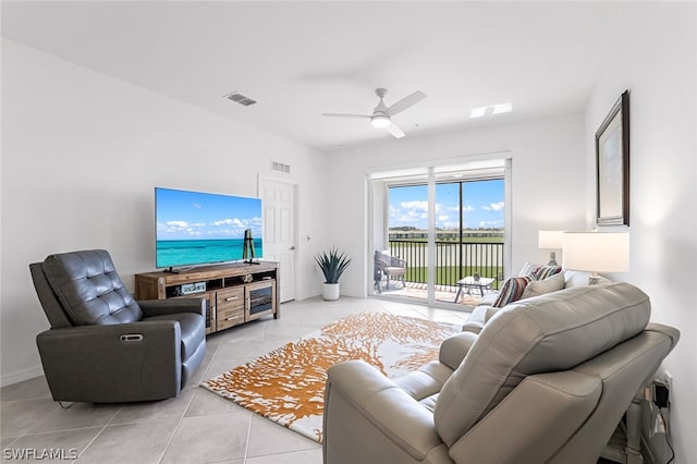 living area featuring light tile patterned floors, ceiling fan, visible vents, and baseboards