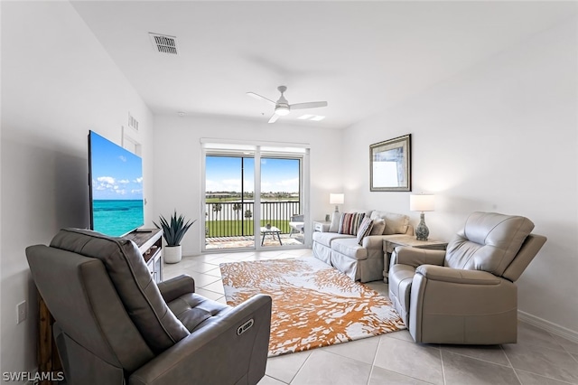 living area with ceiling fan, light tile patterned flooring, visible vents, and baseboards