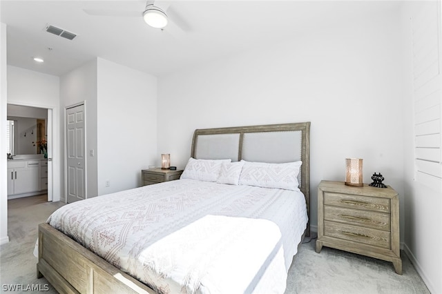 bedroom with light carpet, visible vents, ensuite bath, ceiling fan, and a closet