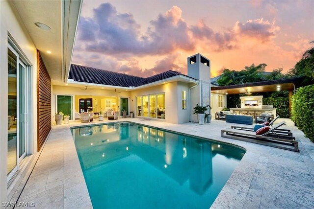 pool at dusk featuring area for grilling and a patio area