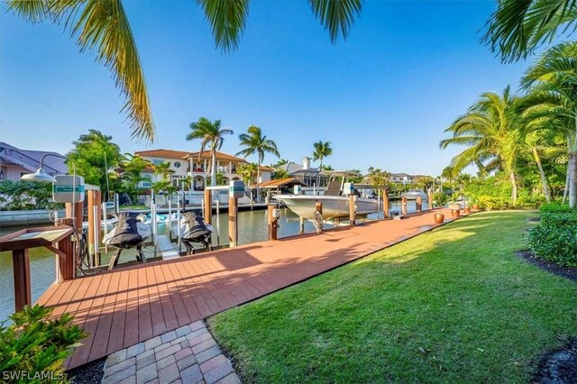 view of dock with a lawn and a water view