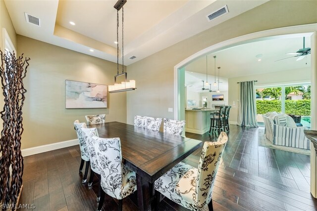 dining room featuring dark hardwood / wood-style floors, ceiling fan, and a tray ceiling