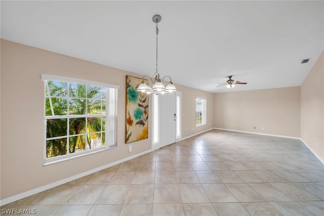 empty room featuring ceiling fan with notable chandelier, a wealth of natural light, and light tile patterned flooring