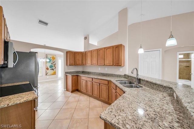 kitchen featuring decorative light fixtures, light stone countertops, light tile patterned flooring, and sink