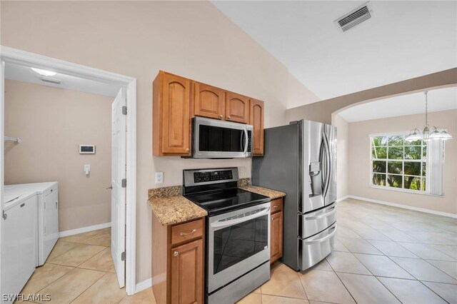 kitchen with appliances with stainless steel finishes, light tile patterned floors, vaulted ceiling, and washing machine and dryer