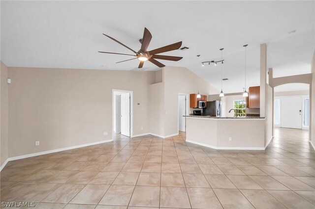 unfurnished living room featuring ceiling fan, sink, light tile patterned floors, and high vaulted ceiling