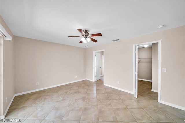 unfurnished bedroom featuring light tile patterned flooring, a spacious closet, ceiling fan, and a closet