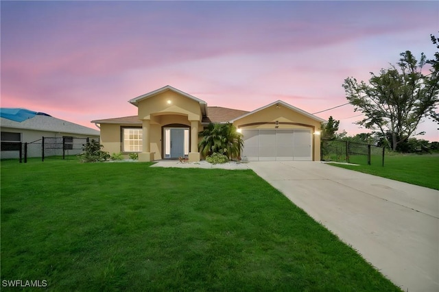 view of front of house with stucco siding, concrete driveway, a yard, and fence