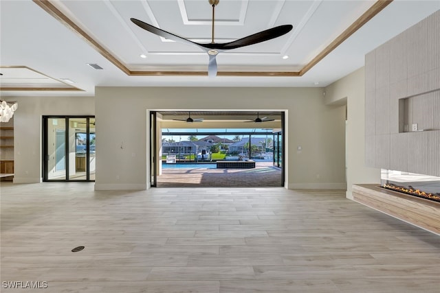 interior space featuring ceiling fan, light hardwood / wood-style floors, ornamental molding, and a tray ceiling