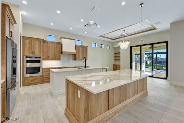 kitchen featuring appliances with stainless steel finishes, custom exhaust hood, a spacious island, sink, and pendant lighting