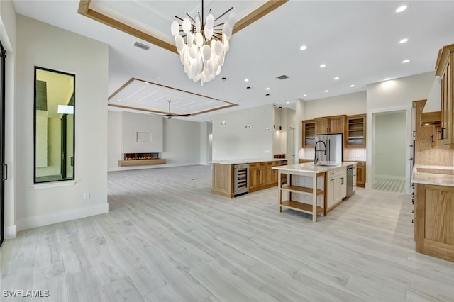 kitchen with a large island, beverage cooler, light hardwood / wood-style flooring, decorative backsplash, and appliances with stainless steel finishes