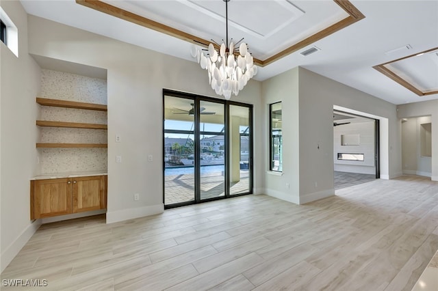 spare room with light hardwood / wood-style floors, a tray ceiling, and an inviting chandelier