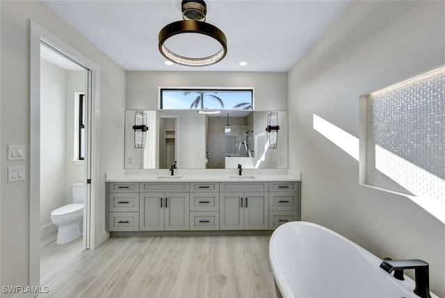 full bathroom with shower with separate bathtub, vanity, hardwood / wood-style flooring, and toilet